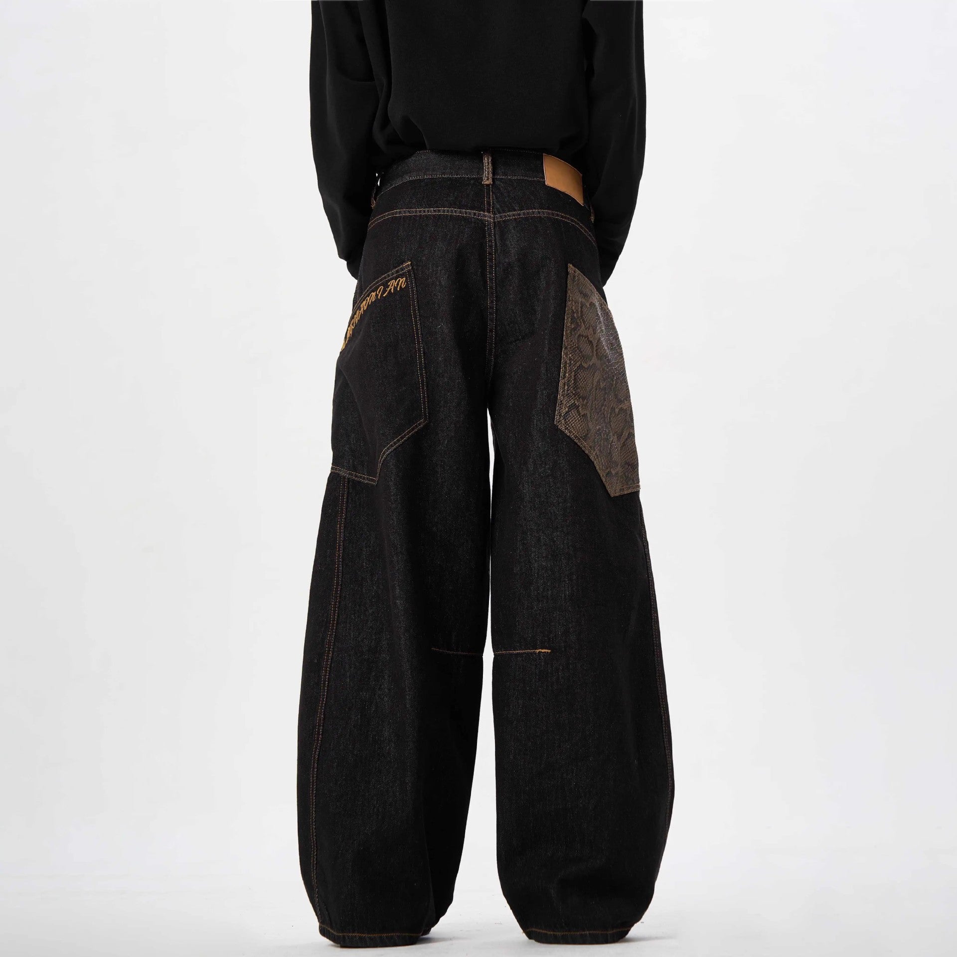 Dark denim jeans with patchwork design on a white background